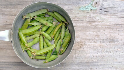 Pea pods in aliminium dish on wooden background