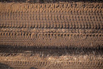 the imprint of the tread on a dirt road. Clay soil, summer day, sunlight