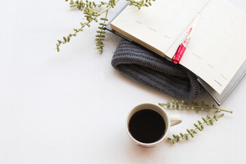 notebook planner  for business work with hot coffee ,knitting wool scarf for winter season on table...