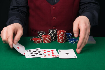 the croupier at the green table removes the playing cards for poker