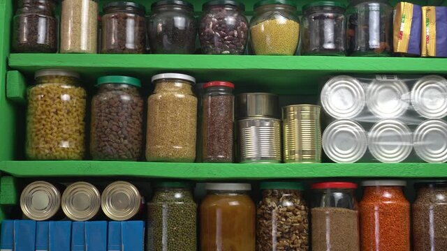Home grocery pantry storage of provision to survive Coronavirus COVID 19 pandemic during quarantine. Panic food buying for lockdown. Canned goods, shelf-stable milk boxes, grains, water bottles