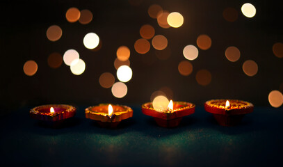 Happy Diwali - Colorful clay diya lamps lit during diwali celebration with glittering bokeh