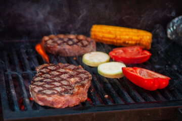 Beef steaks with vegetables on the grill with flames