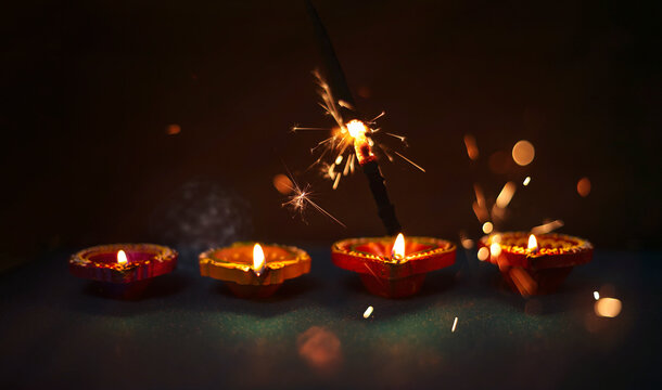 Diya lamps on a reflective base with firecrackers glittering bokeh