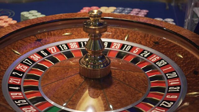 Spinning roulette in casino, top down view, playing chips on table in background