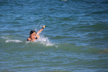 happy boy playing with waves in the sea, horizontal format