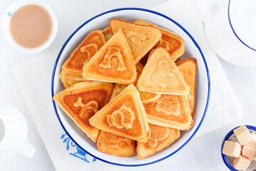 Traditional Russian cookies, cooked on a plate in the form with prints, without baking in an enameled white bowl, selective focus