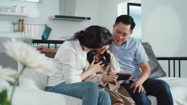 Asian family playing game on smartphone together in the living room.