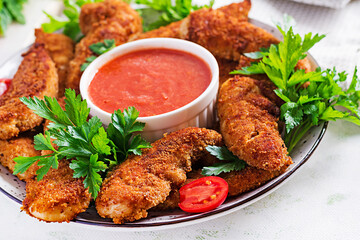 Breaded mini chicken fillets served with tomato sauce. American food. Chicken nuggets with parsley.