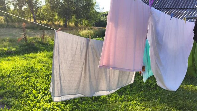 Colorful Laundry Hanging On The Rope Outdoors. The Process Of Air Drying Clothes