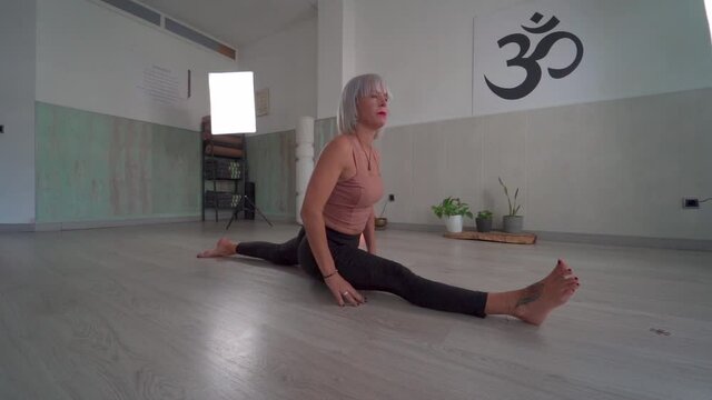 Yoga teacher doing split pose. Hanumanansana or spagt or split position. Girl doing leg split lengthways. Flexible girl. Pan camera movement