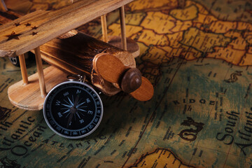 Fototapeta na wymiar Old compass discovery and wooden plane on vintage paper antique world map background, Retro style cartography travel geography navigation, Columbus Day concept