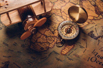 Old compass discovery and wooden plane on vintage paper antique world map background, Retro style...