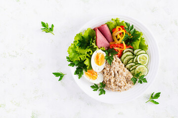 Breakfast oatmeal porridge with boiled egg, ham and vegetables salad. Healthy food. Top view, overhead,  copy space