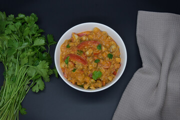 Brazilian fish stew cooked in a delicious, rich and fragrant broth, cilantro, napkin on black baground. Top view.