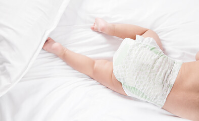 Baby boy in diaper on bed.