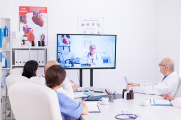 Team of medical staff during video conference with doctor in hospital meeting room. Medicine staff...