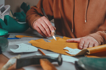 Shoemaker cutting patterns using knife from leather - obrazy, fototapety, plakaty