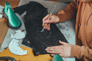Shoemaker cuts patterns from leather at the table