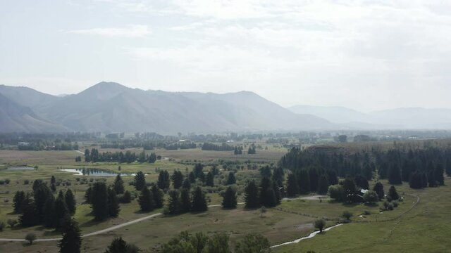 Green Valley near Wyoming Grand Teton. Aerial View of Forest and Meadow on Summer Day. Landscape Outside Jackson City, Drone Shot flying low towards Farm House Ranch Where Harrison Ford Lives.