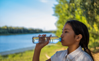 Young healthy woman drinks water from bottle.Outdoor