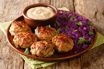 Delicious fried meatballs with hot stewed red cabbage and sauce close-up in a plate on the table. horizontal