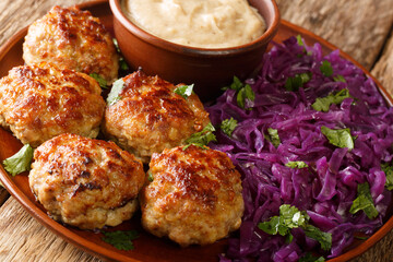 Fried Danish meatballs with hot stewed red cabbage and sauce close-up in a plate on the table. horizontal