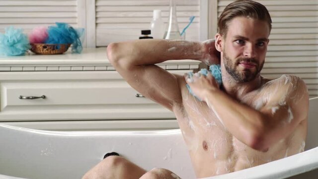 Sexy young man washing in bathrobe in bathroom. Hygiene and spa. Sexy sport muscle strongface guy. Nude bare torso.