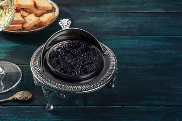 Caviar in a vintage bowl with toasts, with a place for text on a dark blue wooden background