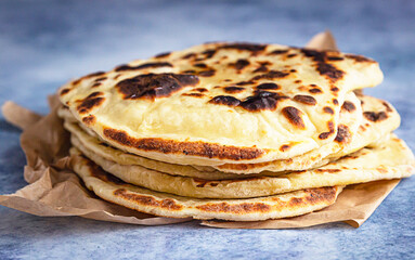 Stack of homemade crispy flatbread, blue concrete background.