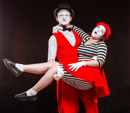 Portrait of two mime artists, isolated on black background. Man holds woman in his arms. Symbol of happy marriage, sweet couple, love, family