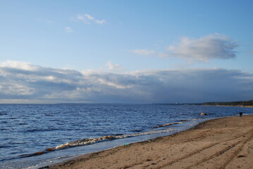 Sunny day. Magnificent views of the beach and the Gulf of Finland. Blue water and yellow sand. Clouds.