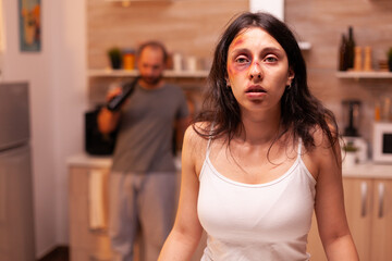 Vulnerable woman after being beaten and traumatised by violent drunk husband. Violent aggressive man abusing injuring terrified helpless, vulnerable, afraid, beaten and panicked wife.