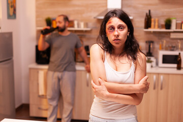 Abused woman being depressive and trembled because of husband agression. Violent aggressive man sing injuring terrified helpless, vulnerable, afraid, beaten and panicked wife, victim.