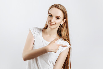 Young beautiful girl smiling and showing finger to the side on gray isolated background
