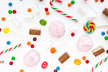 Many different sweets on a white background. Multicolored lollipops, caramel, candy canes, marshmallows, chocolate top view