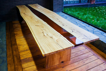 Large long wooden table with epoxy fill in the evening in a modern loft style home interior. View...