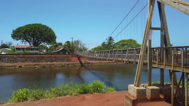 4K slight left to right panning motion of woman crossing the Hanapepe swinging bridge, Wooden bridge built in early 1900,Kauai,Hawaii,USA