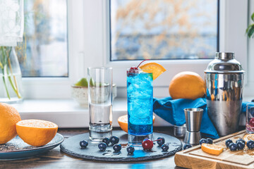 Blue gin tonic cocktail with ice a mix of alcohol near the window on the table near window in the sun falltime. Real life in new reality in under quarantine