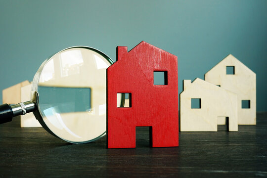 Estimating the value of real estate. Small house and magnifying glass.