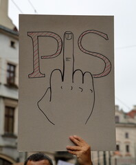 Banner with rough visual opinion about Polish ruling party Law and Justice hold by male hand during...