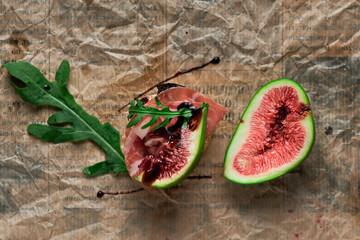 Bruschetta with prosciutto ham, ricotta cheese, arugula and fresh figs on a dark paper background....