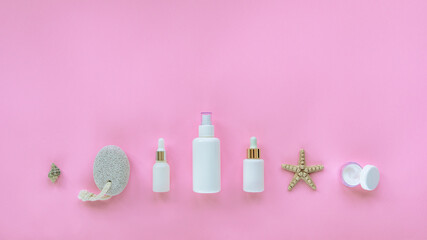 Natural organic beauty skincare products. Serum, cream jar, tonic, cosmetic oil in white unbranded bottles, pumice stone, seashell. Pink background, top view, flat lay, copy space
