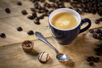 Espresso on a wooden table with coffee beans and chocolates