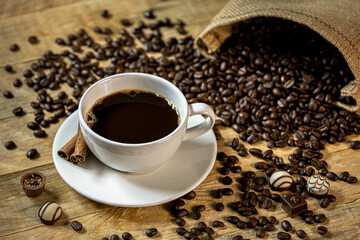 Dark coffee on a wooden table with coffee beans and chocolates