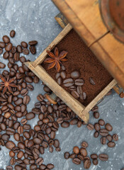 top view on old coffee grinder full of coffee and beans with spices on grey marble