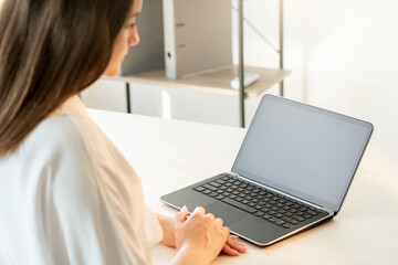 Distance learning. Online education. Zoom videocall. Digital technology. Confident woman study using laptop with black blank screen at cosy light workplace.