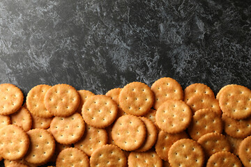 Tasty cracker biscuits on black smoky background, space for text