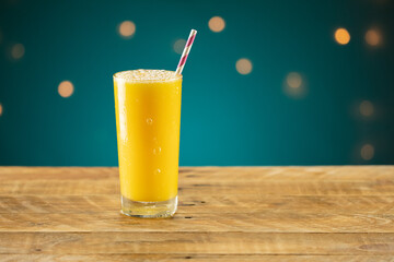 Orange juice on a wooden table with a straw