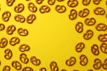 Tasty cracker pretzels on yellow background, top view